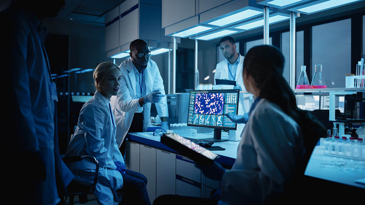 A diverse team of scientists use a digital tablet computer discussing innovative biotechnology.